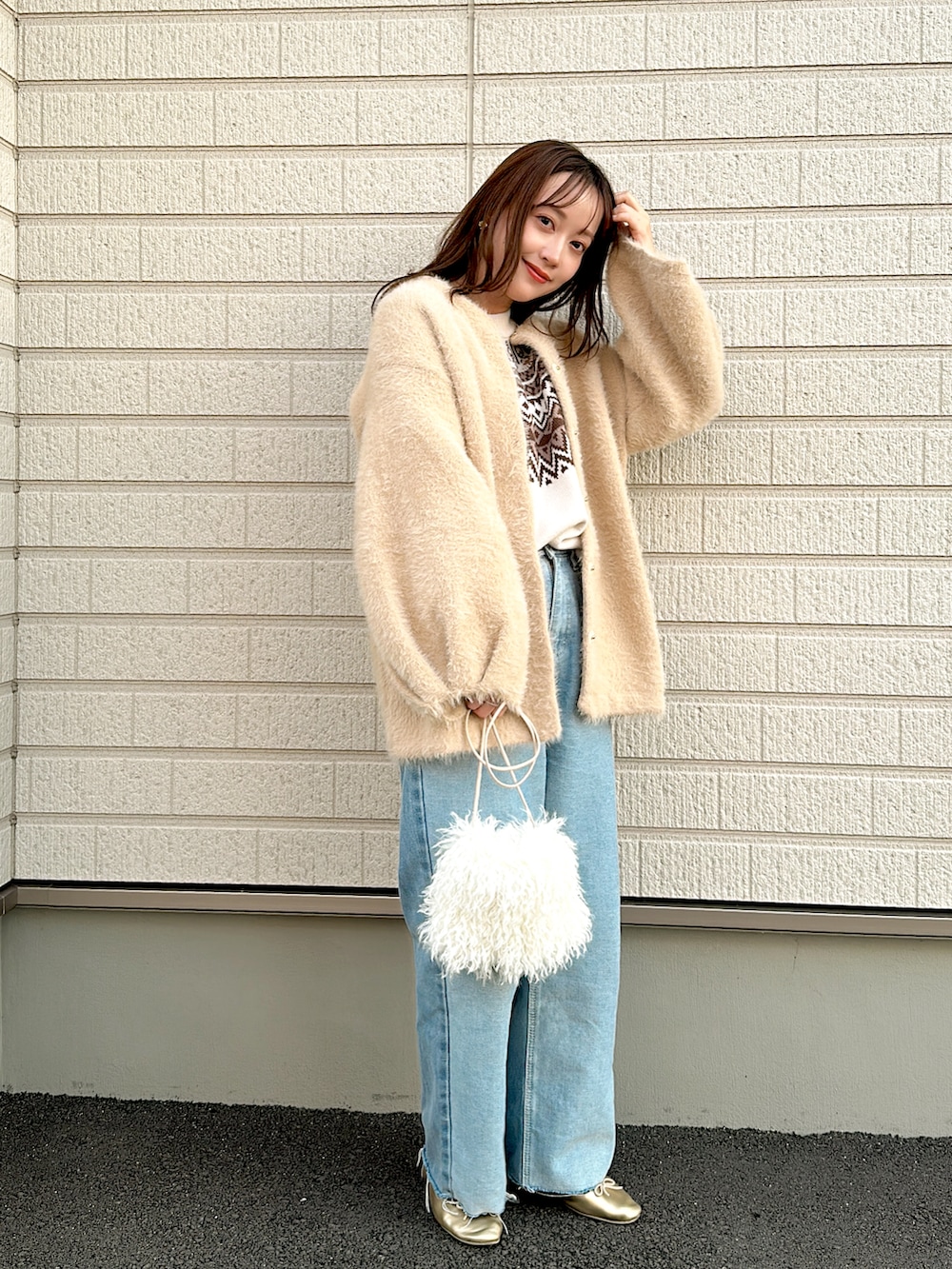 ベージュ系のノーカラーコート、ホワイト系のニット/セーター、ブルー系のデニムパンツを着用したレディースの秋コーディネートの2枚目の写真