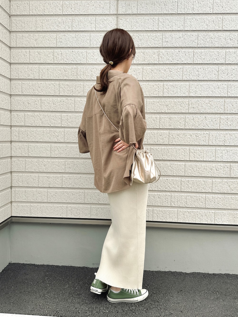 ベージュ系のスカート、ゴールド系のショルダーバッグ、グリーン系のスニーカーを着用したレディースの春コーディネートの2枚目の写真