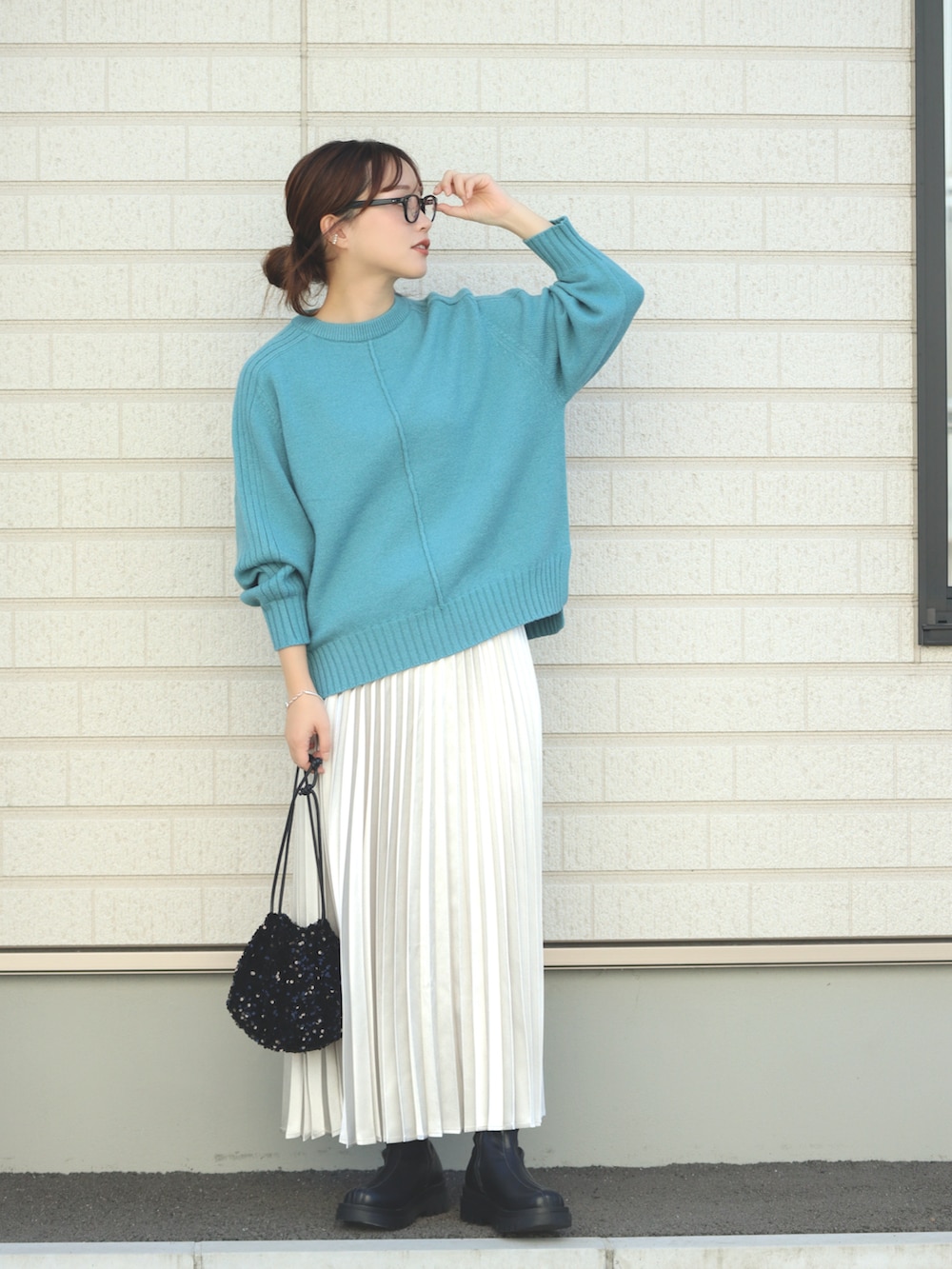 グレー系のスカート、ブラック系のショルダーバッグ、ブラック系のブーツを着用したレディースの秋コーディネートの2枚目の写真