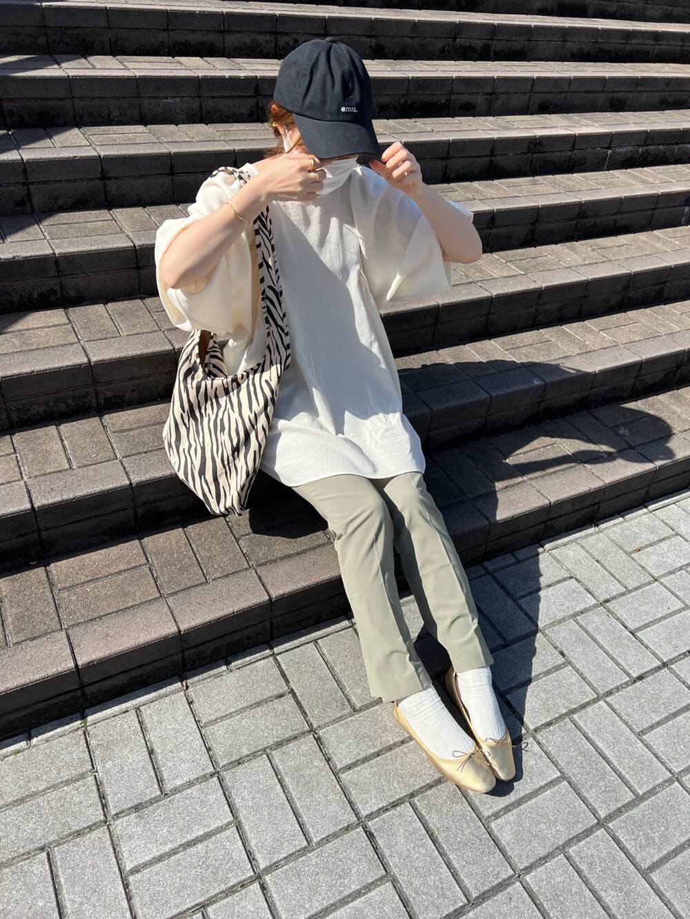 ホワイト系のトップス、その他のトートバッグ、グリーン系のスラックスを着用したレディースの春コーディネートの2枚目の写真