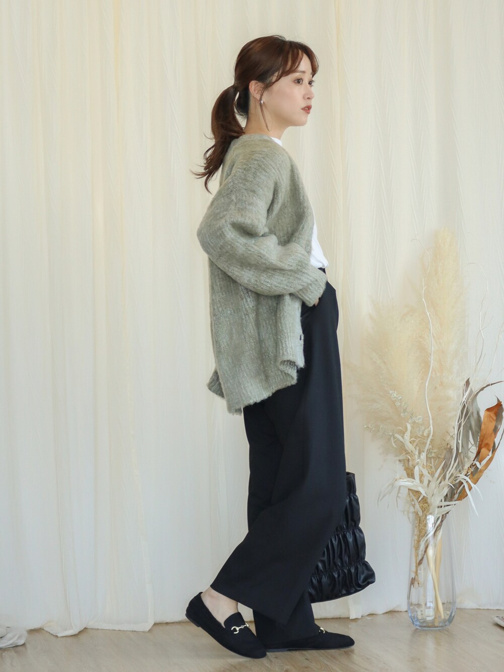 グリーン系のカーディガン/ボレロ、ブラック系のパンツ、ブラック系のバッグを着用したレディースの秋コーディネートの3枚目の写真