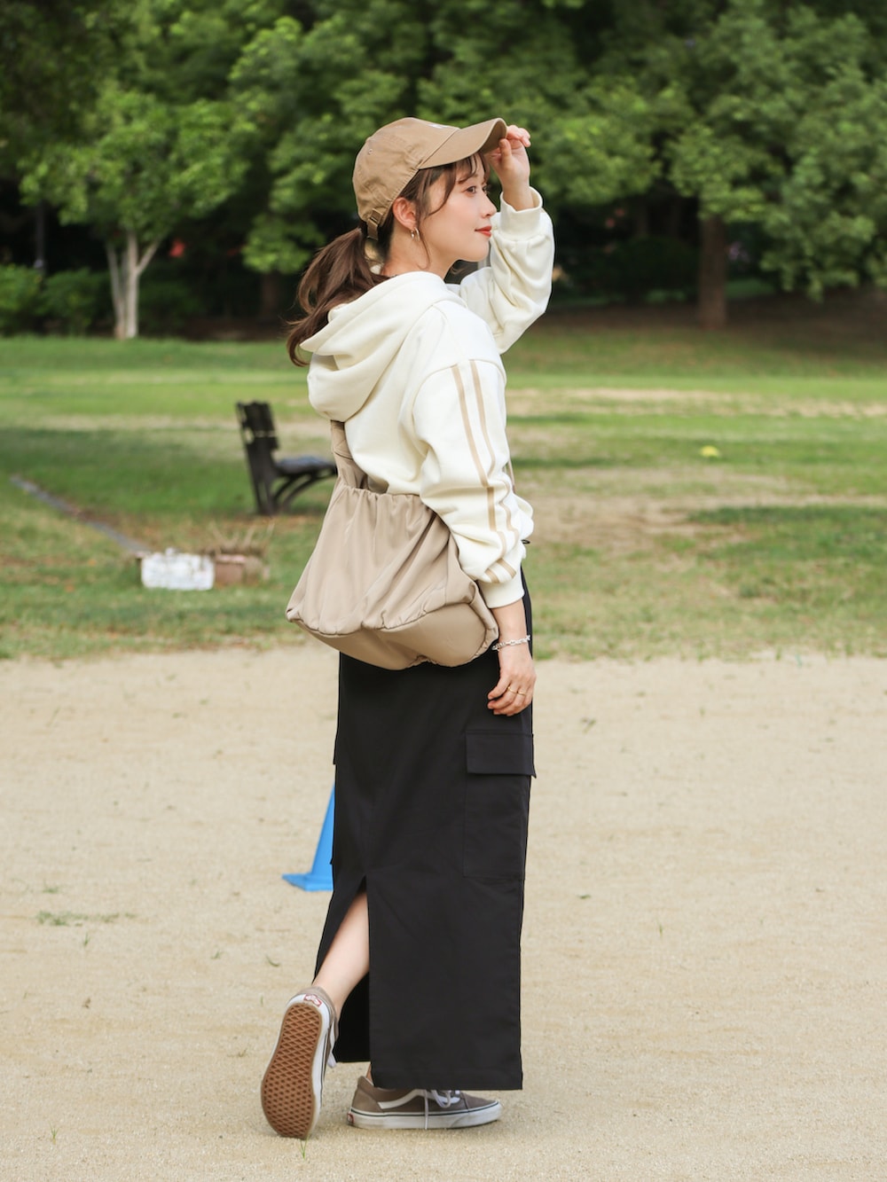 ブラック系のスカート、ホワイト系のパーカー、ベージュ系のバッグを着用したレディースの秋コーディネートの2枚目の写真