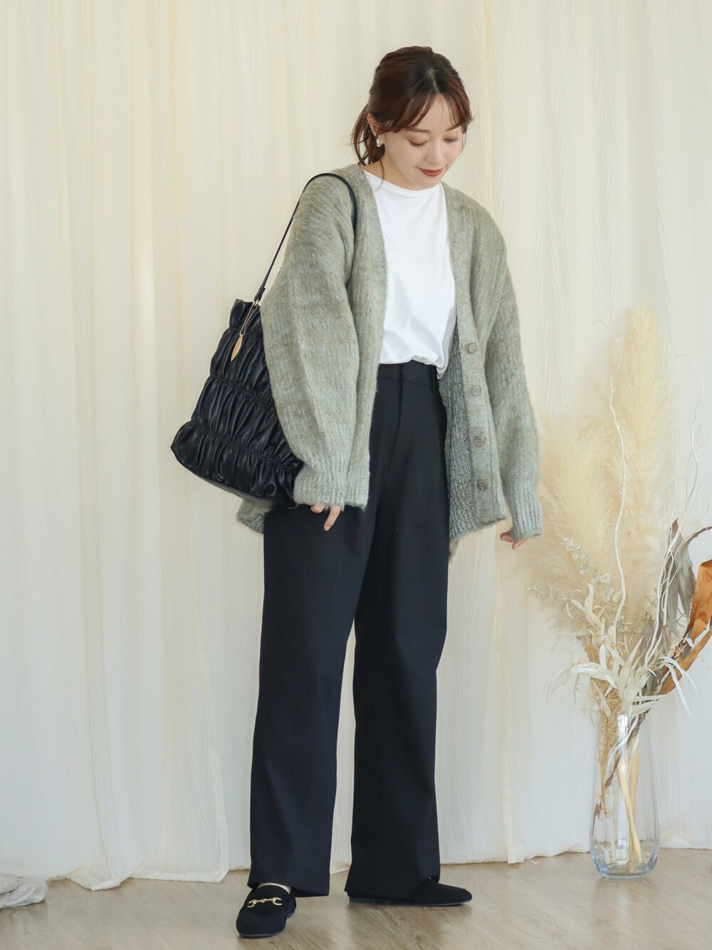 グリーン系のカーディガン/ボレロ、ブラック系のパンツ、ブラック系のバッグを着用したレディースの秋コーディネートの2枚目の写真