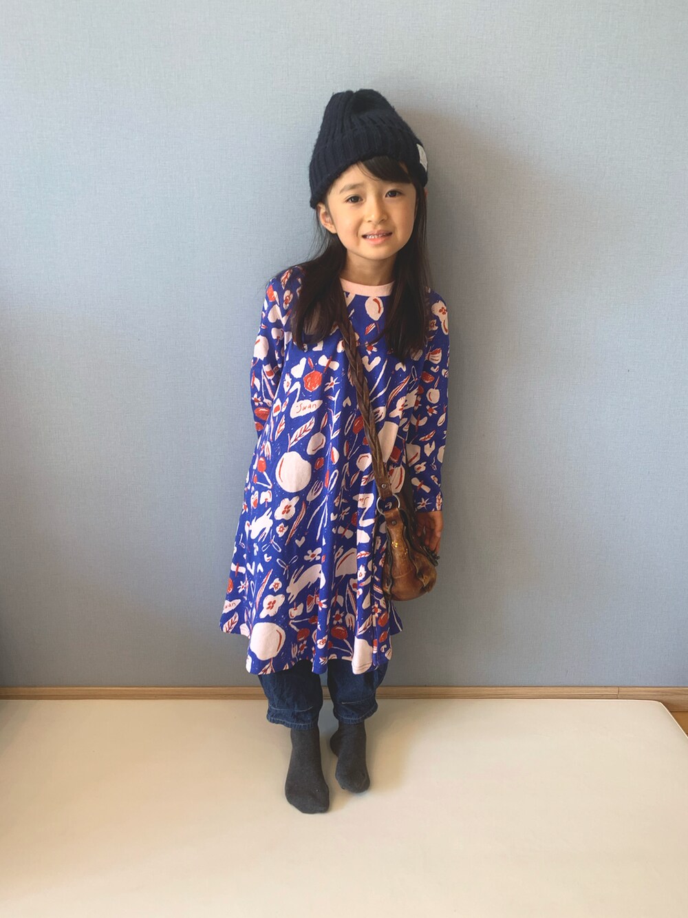 ブルー系のワンピース、ブルー系のデニムパンツ、ブラウン系のショルダーバッグを着用したキッズの秋コーディネートの2枚目の写真