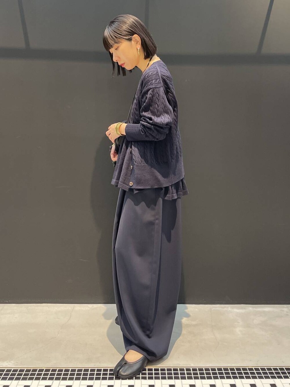 ブルー系のカーディガン/ボレロ、ブルー系のその他パンツ、ブラック系のクラッチバッグを着用したレディースの秋コーディネートの3枚目の写真