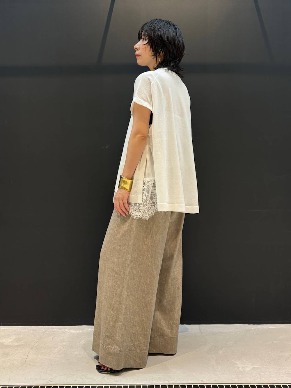 ベージュ系のその他パンツ、ホワイト系のニット/セーター、ゴールド系のバングル/リストバンドを着用したレディースの夏コーディネートの2枚目の写真