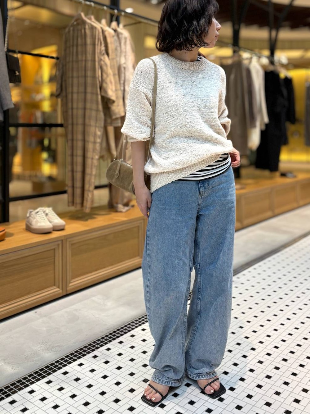 ブルー系のデニムパンツ、ブラック系のタンクトップ、ホワイト系のニット/セーターを着用したレディースの春コーディネートの2枚目の写真