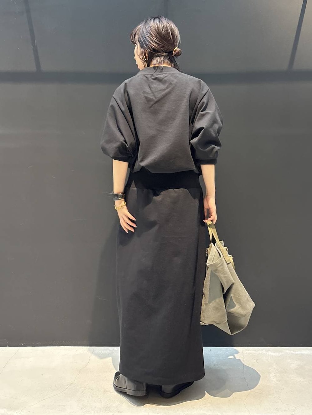 グリーン系のトートバッグ、ブラック系のワンピース、ブラック系のブレスレットを着用したレディースの冬コーディネートの3枚目の写真