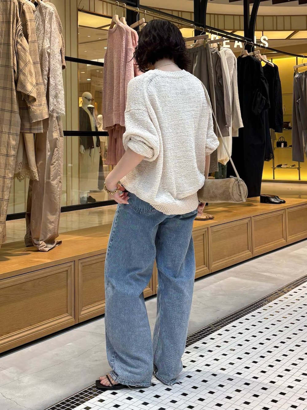 ブルー系のデニムパンツ、ブラック系のタンクトップ、ホワイト系のニット/セーターを着用したレディースの春コーディネートの4枚目の写真