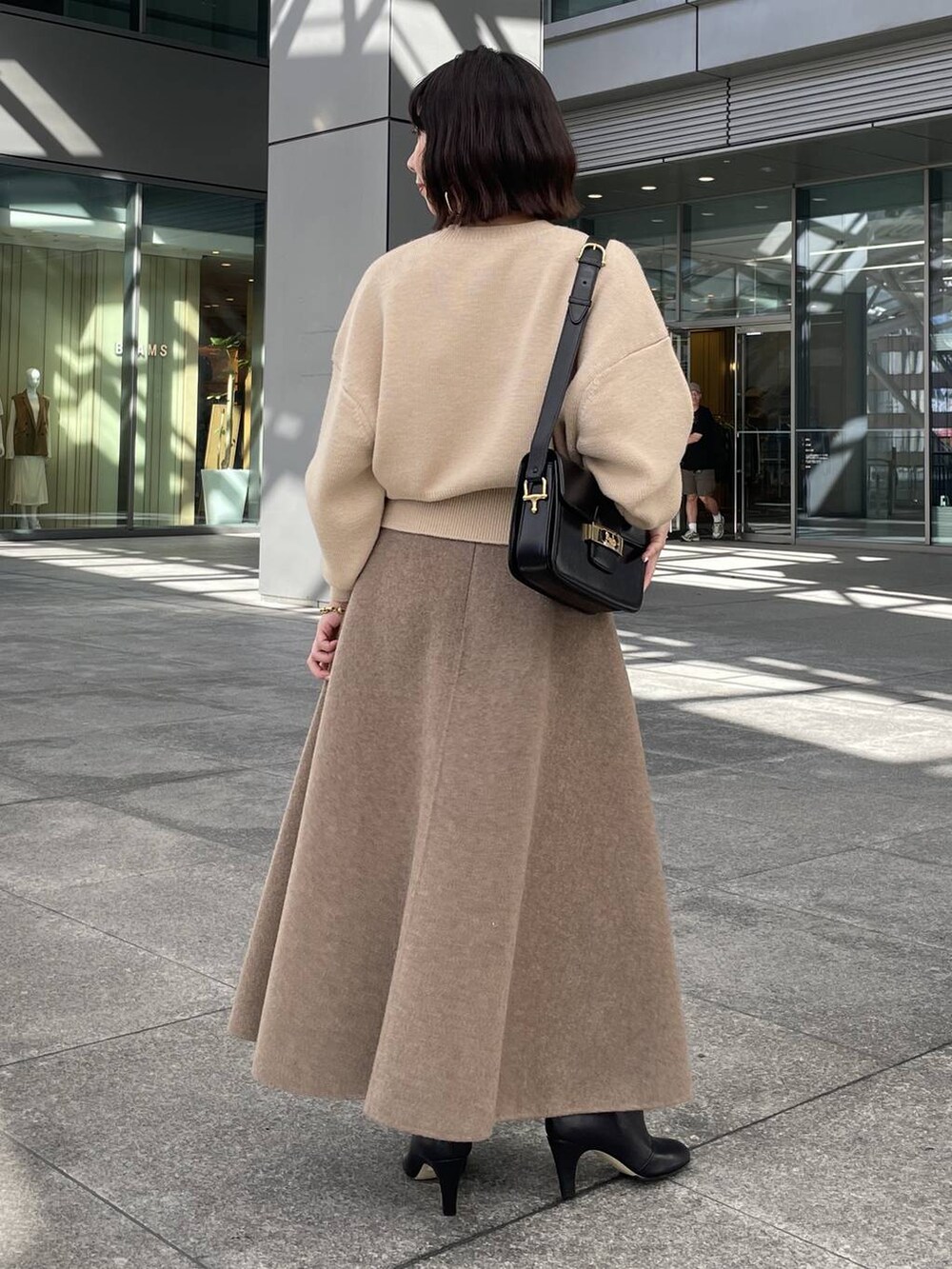 ベージュ系のニット/セーター、ベージュ系のスカート、ゴールド系のブレスレットを着用したレディースの秋コーディネートの3枚目の写真