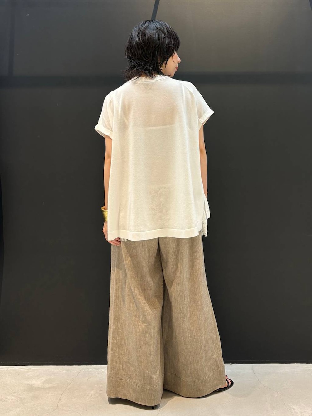 ベージュ系のその他パンツ、ホワイト系のニット/セーター、ゴールド系のバングル/リストバンドを着用したレディースの夏コーディネートの3枚目の写真