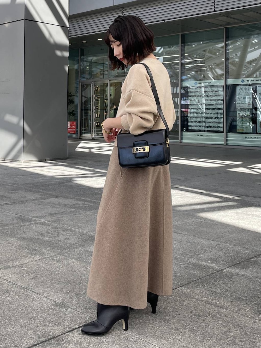 ベージュ系のニット/セーター、ベージュ系のスカート、ゴールド系のブレスレットを着用したレディースの秋コーディネートの2枚目の写真