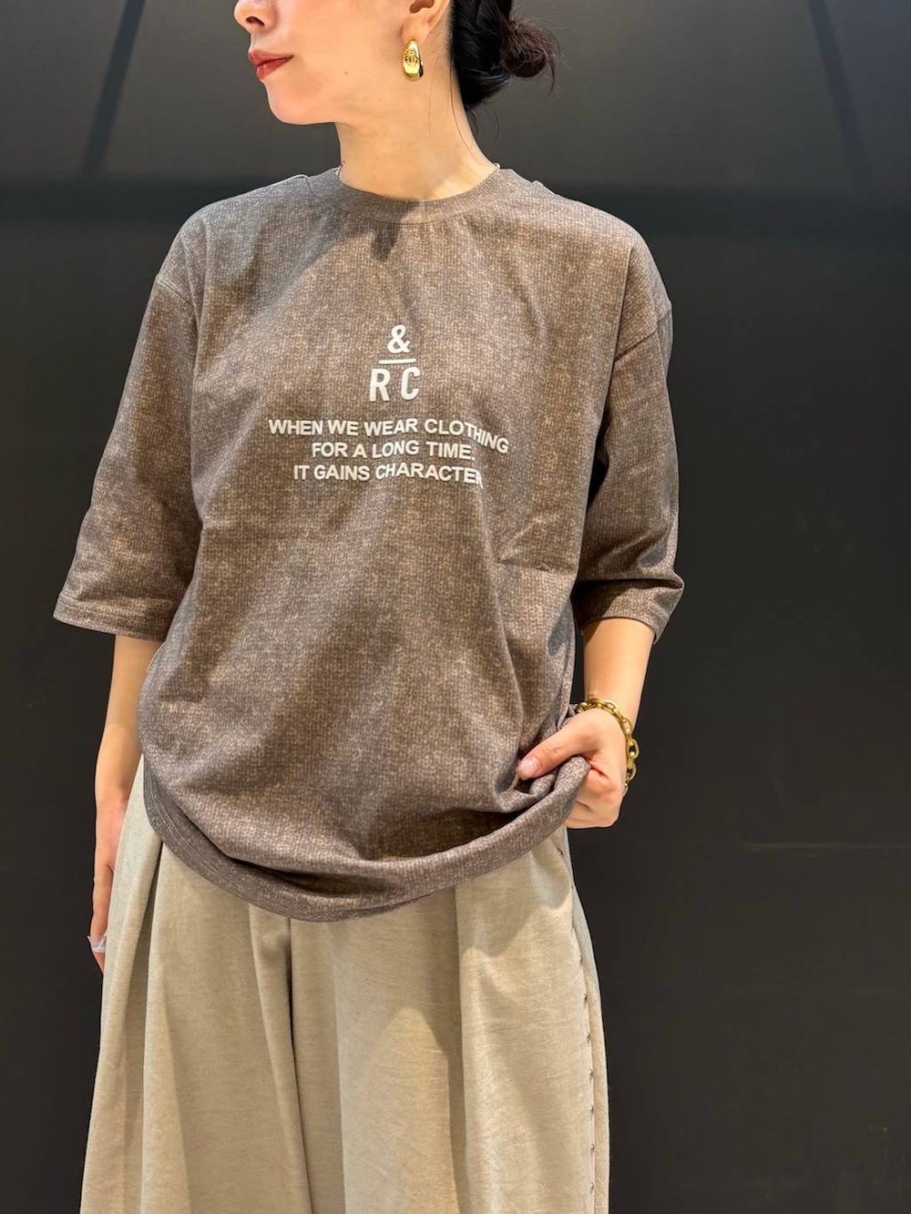 ベージュ系のその他パンツ、ブラウン系のTシャツ/カットソー、ゴールド系のピアス（両耳用）を着用したレディースの夏コーディネートの2枚目の写真