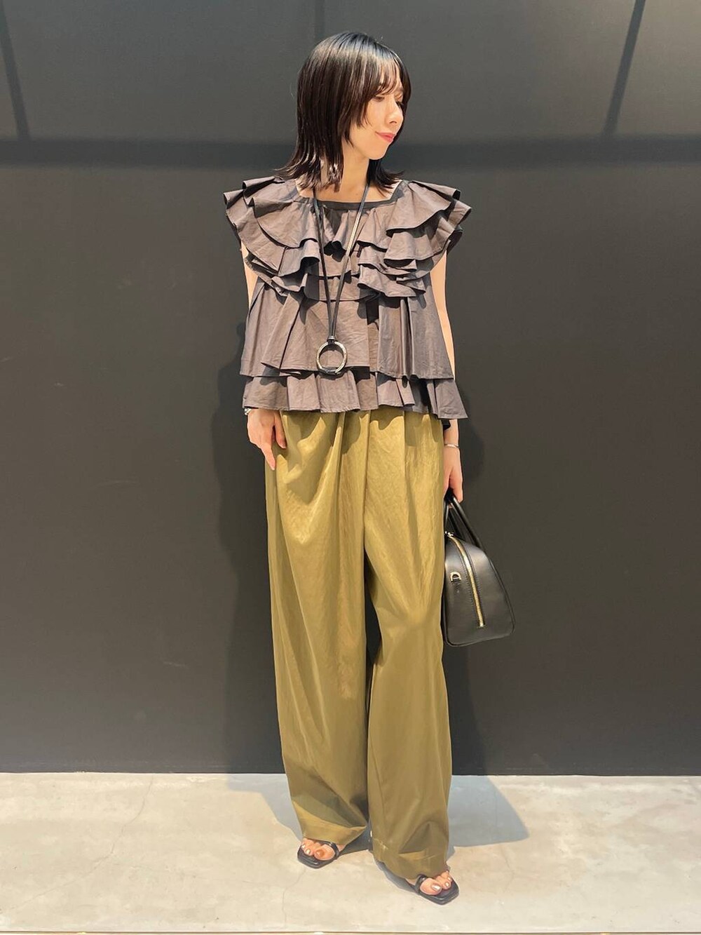 ベージュ系のその他パンツ、グレー系のシャツ/ブラウス、ブラック系のネックレスを着用したレディースの夏コーディネートの4枚目の写真