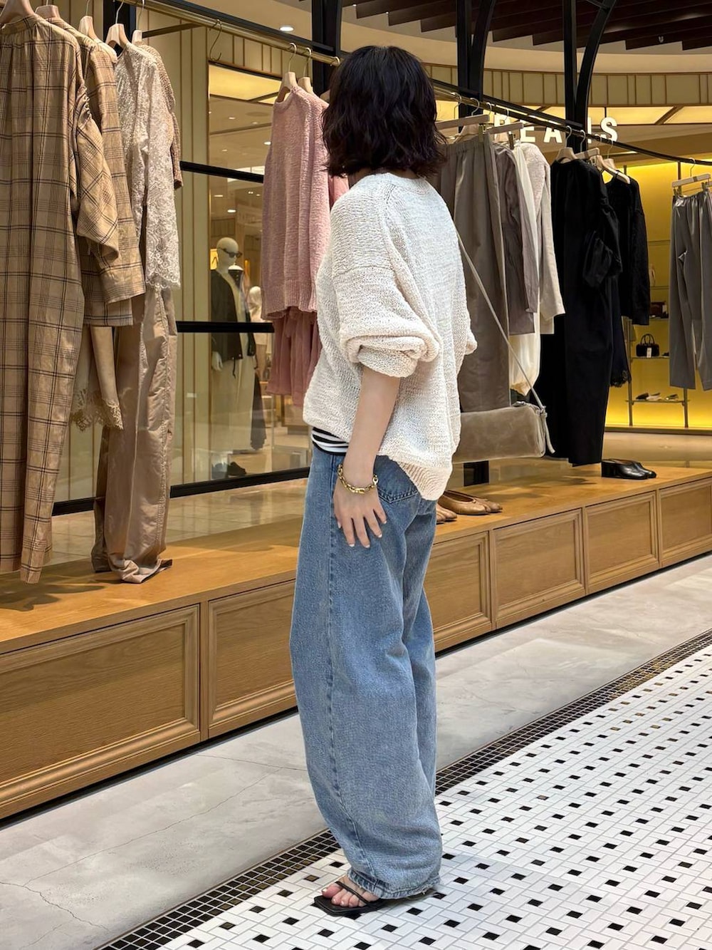 ブルー系のデニムパンツ、ブラック系のタンクトップ、ホワイト系のニット/セーターを着用したレディースの春コーディネートの3枚目の写真