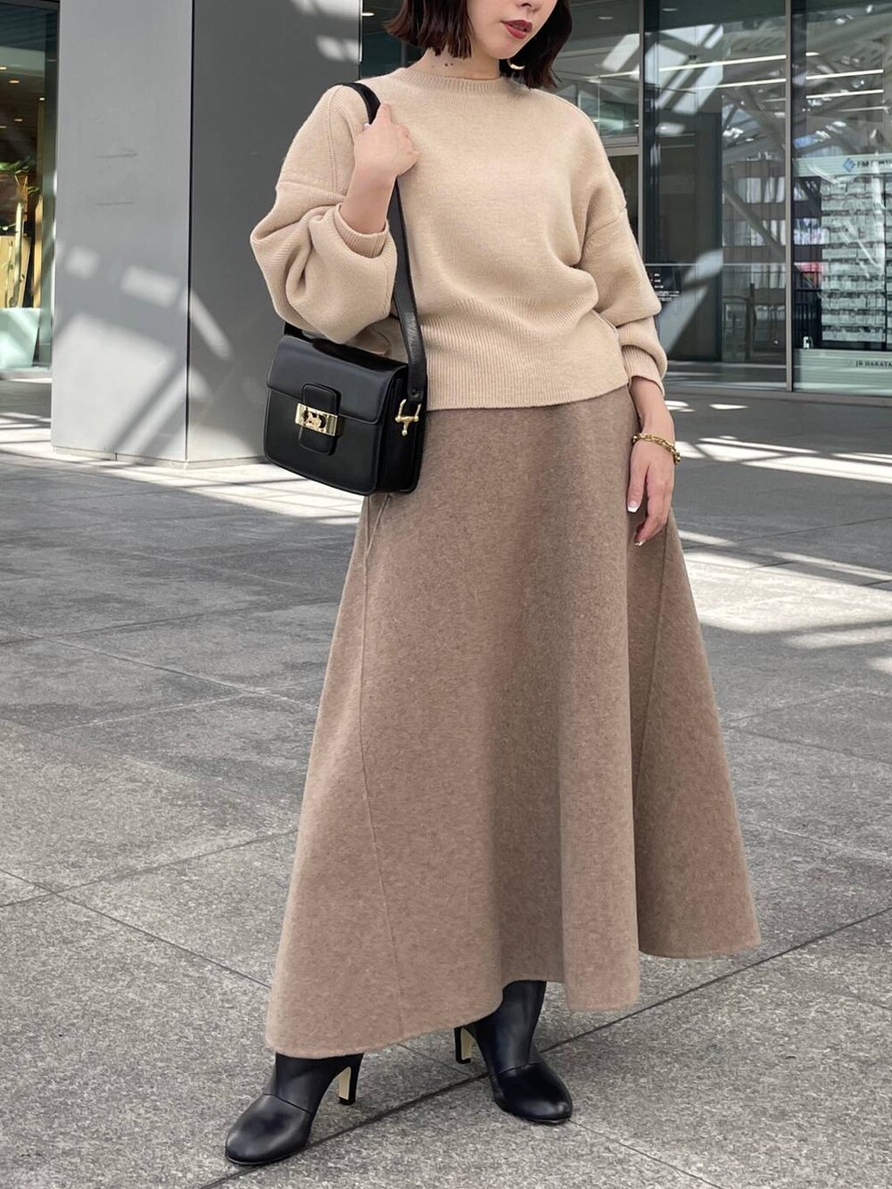 ベージュ系のニット/セーター、ベージュ系のスカート、ゴールド系のブレスレットを着用したレディースの秋コーディネートの5枚目の写真