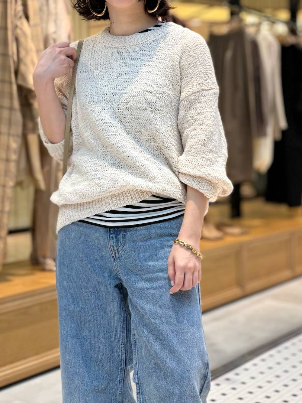 ブルー系のデニムパンツ、ブラック系のタンクトップ、ホワイト系のニット/セーターを着用したレディースの春コーディネートの5枚目の写真