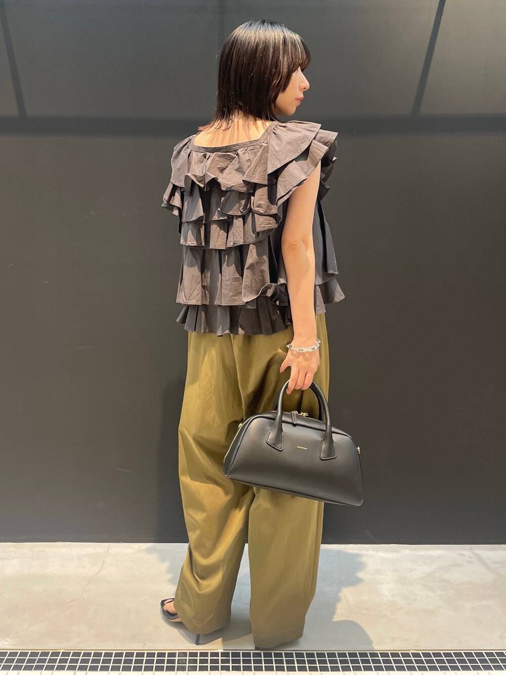 ベージュ系のその他パンツ、グレー系のシャツ/ブラウス、ブラック系のネックレスを着用したレディースの夏コーディネートの3枚目の写真