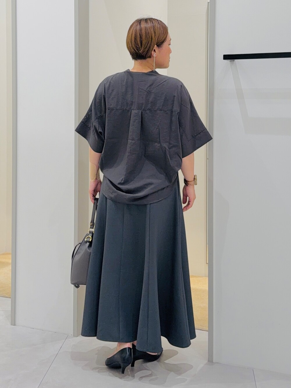 ブラック系のシャツ/ブラウス、グレー系のスカート、グレー系のショルダーバッグを着用したレディースの夏コーディネートの5枚目の写真