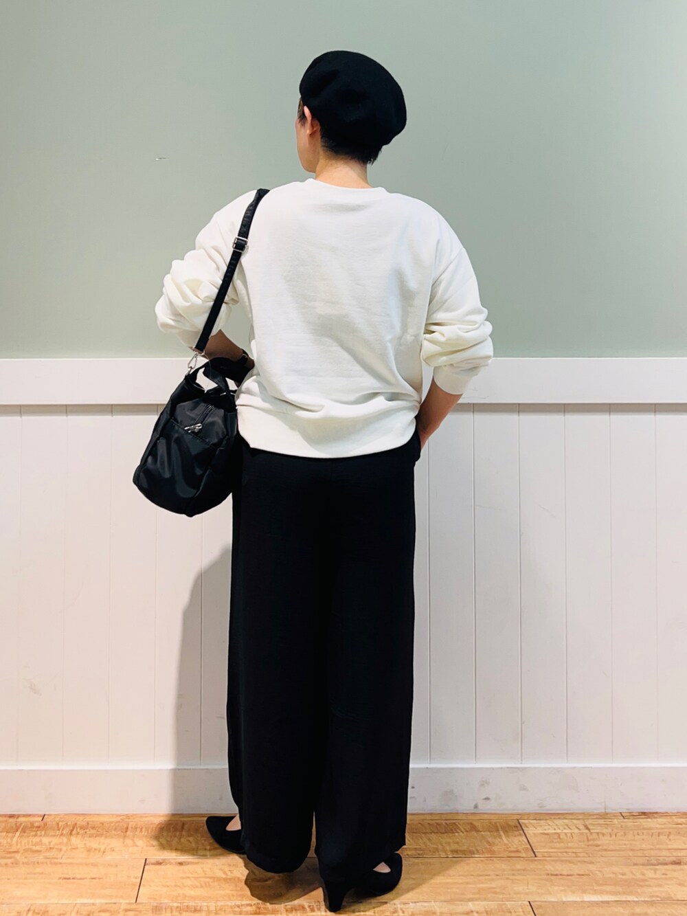 ホワイト系のスウェット、ブラック系のトートバッグ、ブラック系のパンツを着用したレディースの秋コーディネートの3枚目の写真