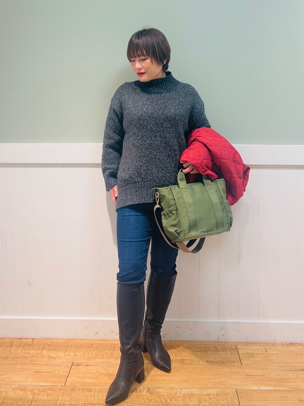 グレー系のニット/セーター、ブルー系のデニムパンツ、グリーン系のトートバッグを着用したレディースの冬コーディネートの4枚目の写真
