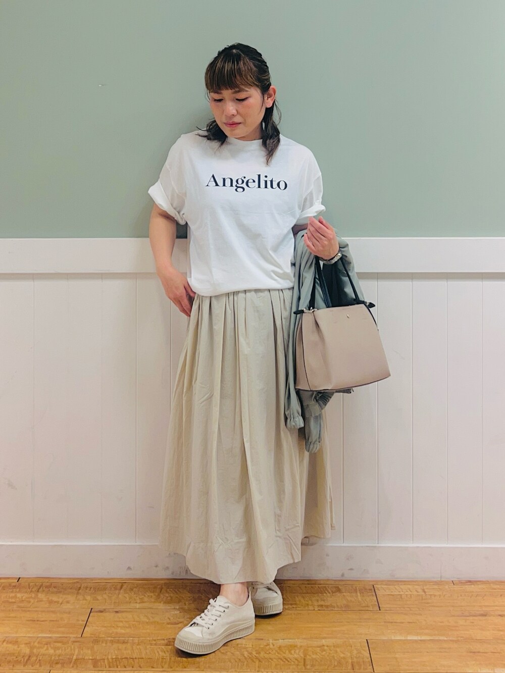 ホワイト系のTシャツ/カットソー、グリーン系のブルゾン、ベージュ系のスカートを着用したレディースの春コーディネートの3枚目の写真