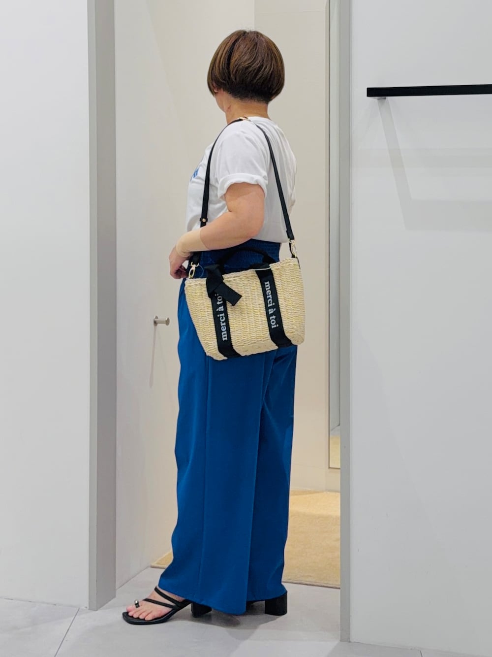 ホワイト系のTシャツ/カットソー、ブルー系のその他パンツ、ベージュ系のハンドバッグを着用したレディースの夏コーディネートの3枚目の写真