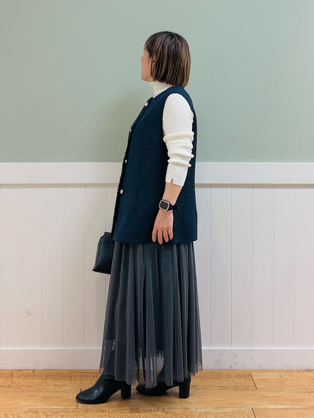 ホワイト系のニット/セーター、ブルー系のベスト、ブラック系のトートバッグを着用したレディースの冬コーディネートの4枚目の写真