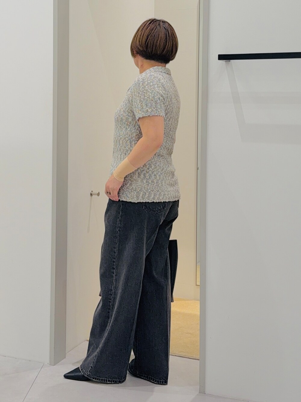 グレー系のニット/セーター、ブラック系のデニムパンツ、ブラック系のトートバッグを着用したレディースの夏コーディネートの3枚目の写真