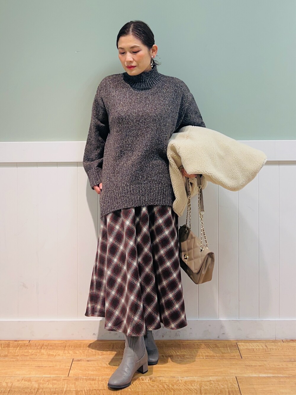 ブラウン系のニット/セーター、ホワイト系のブルゾン、ブラウン系のスカートを着用したレディースの冬コーディネートの3枚目の写真