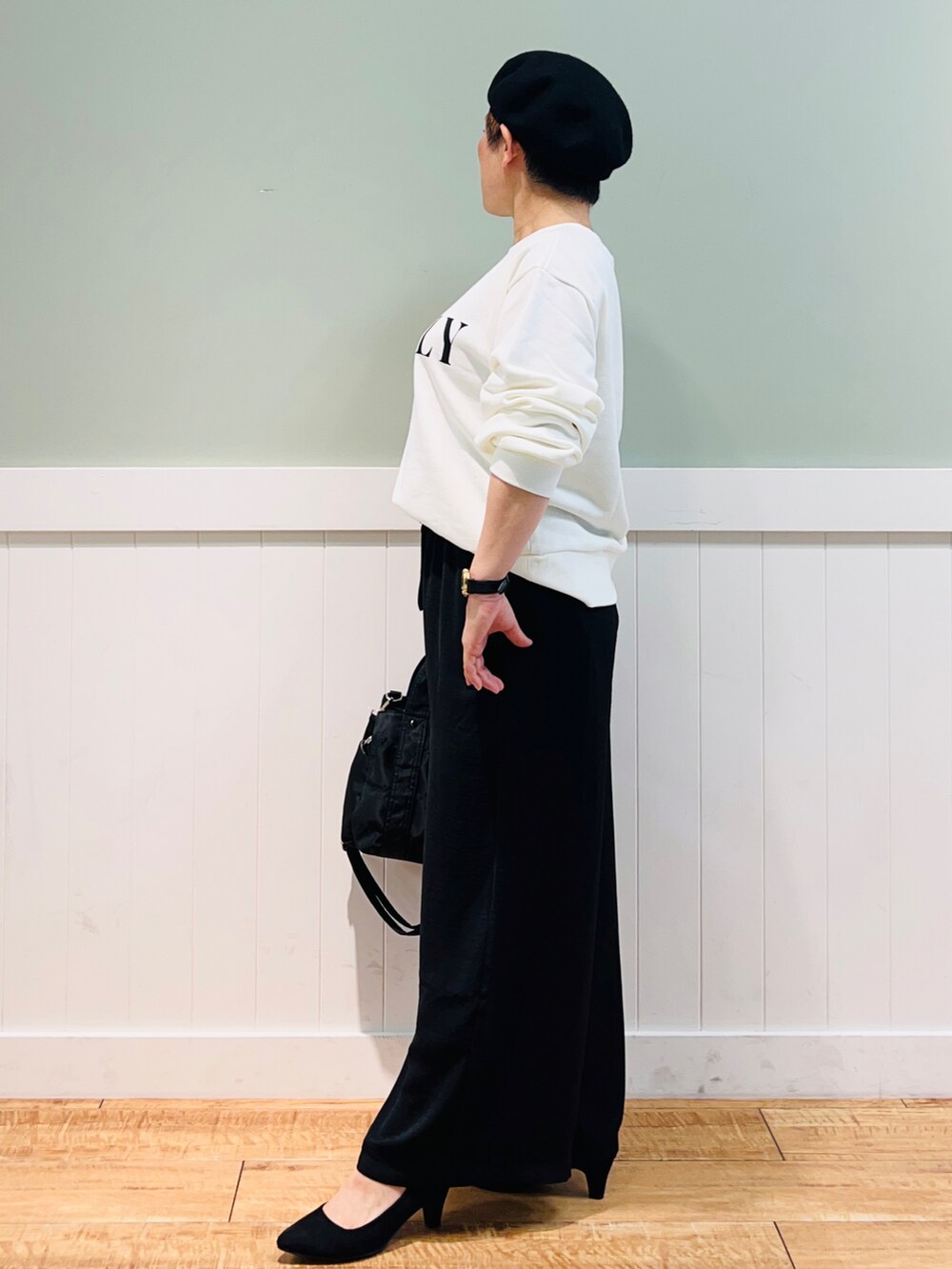 ホワイト系のスウェット、ブラック系のトートバッグ、ブラック系のパンツを着用したレディースの秋コーディネートの2枚目の写真