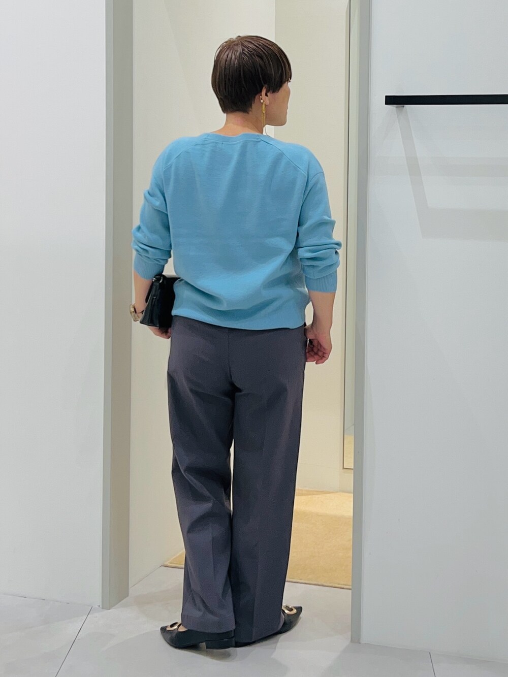 ブルー系のニット/セーター、ブラック系のショルダーバッグ、ブラック系のパンプスを着用したレディースの秋コーディネートの4枚目の写真