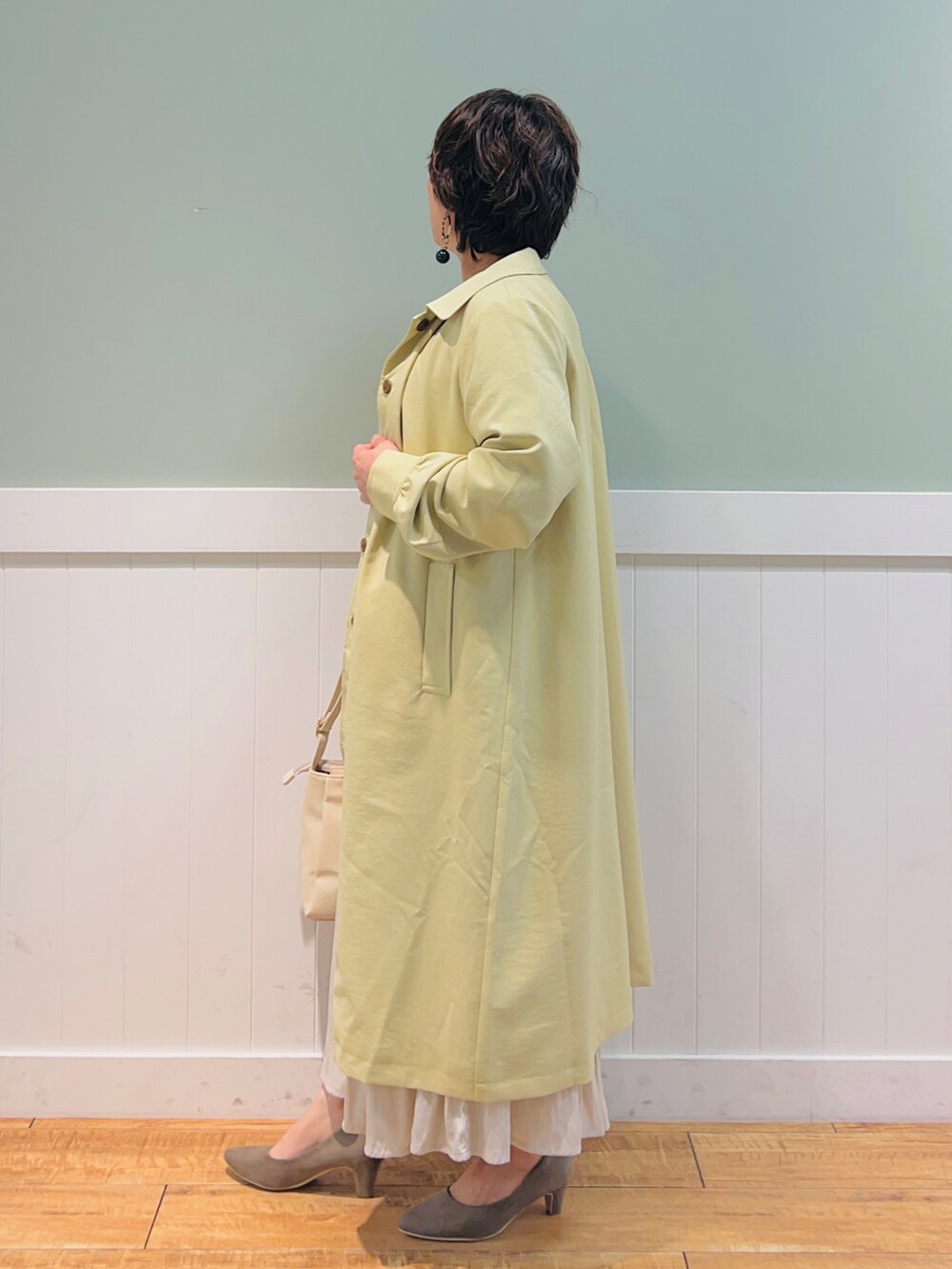 ベージュ系のその他トップス、イエロー系のステンカラーコート、ベージュ系のスカートを着用したレディースの春コーディネートの2枚目の写真