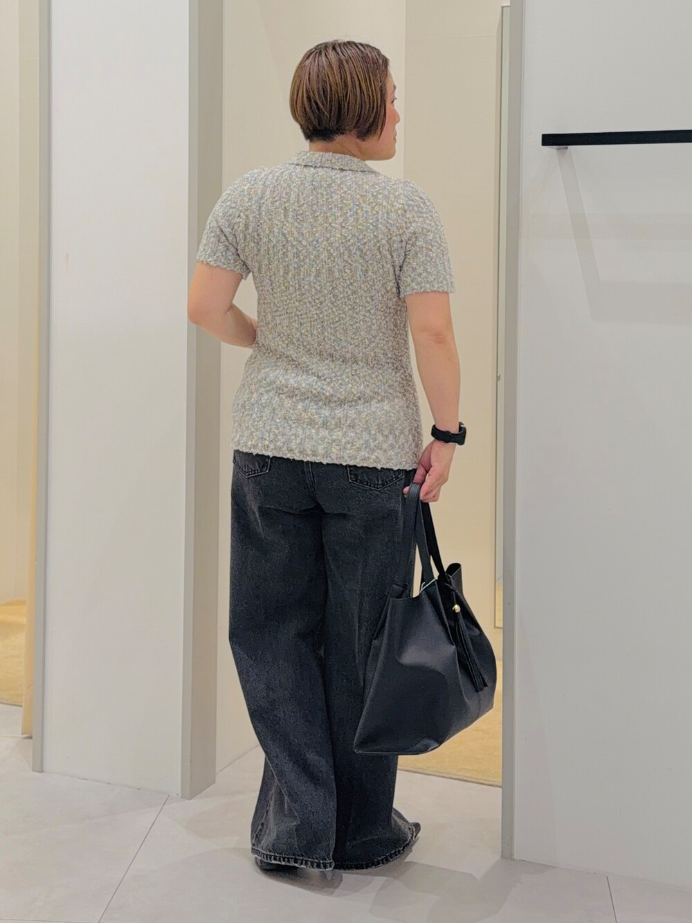 グレー系のニット/セーター、ブラック系のデニムパンツ、ブラック系のトートバッグを着用したレディースの夏コーディネートの4枚目の写真