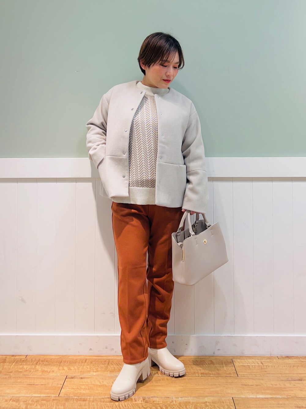ベージュ系のノーカラーコート、ホワイト系のニット/セーター、グレー系のトートバッグを着用したレディースの冬コーディネートの4枚目の写真