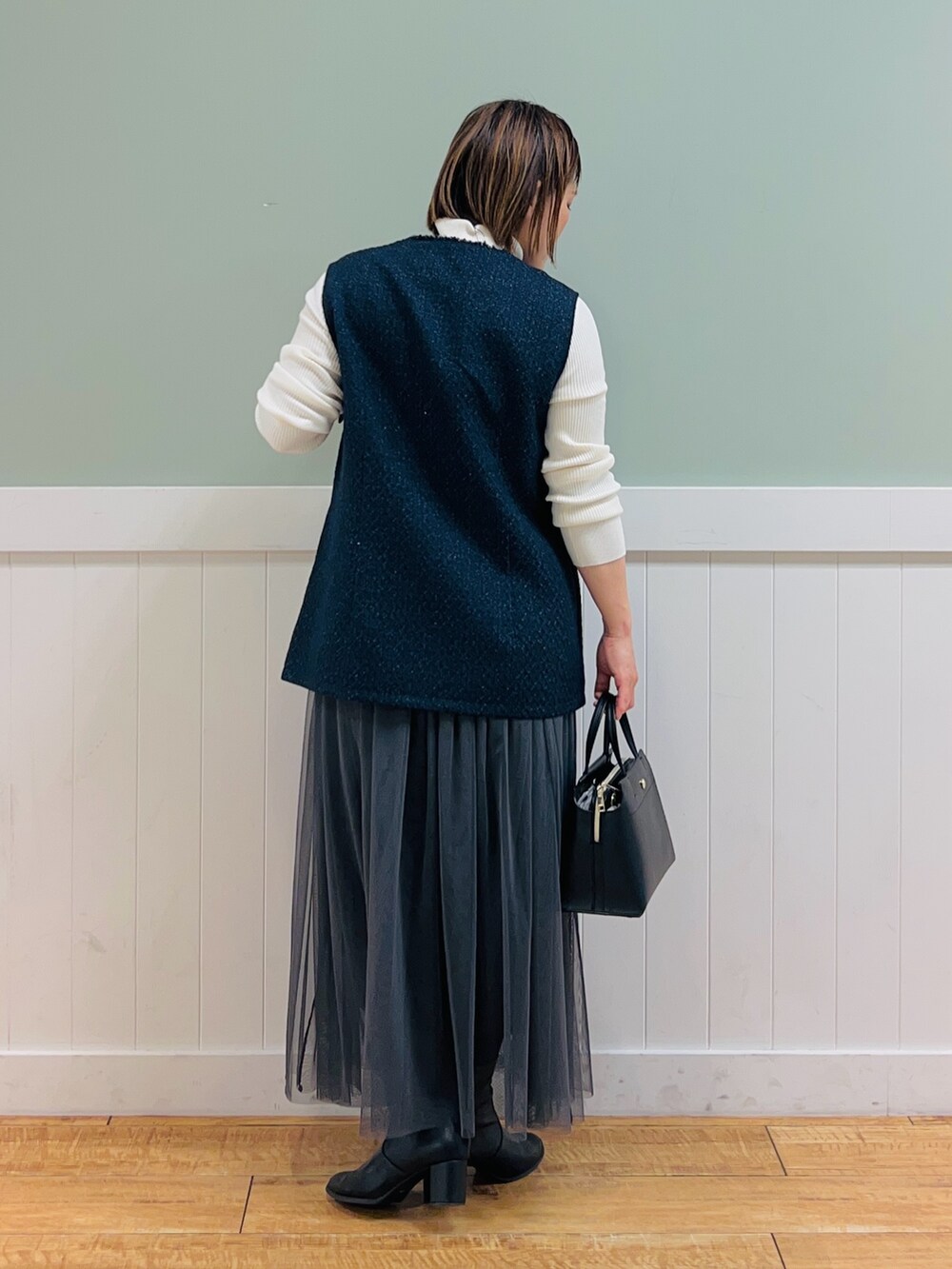 ホワイト系のニット/セーター、ブルー系のベスト、ブラック系のトートバッグを着用したレディースの冬コーディネートの5枚目の写真