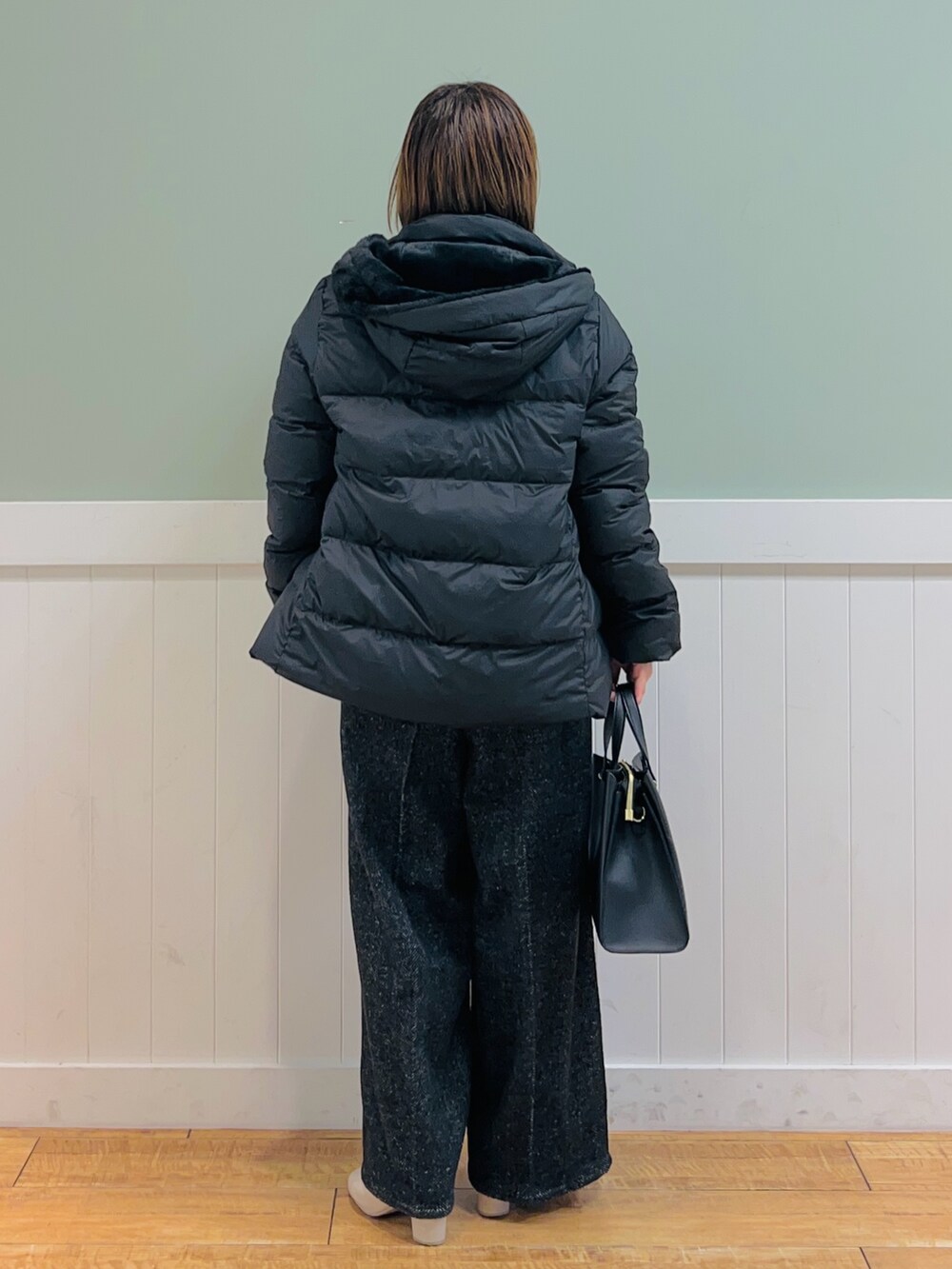 ブラック系のダウンジャケット/コート、ホワイト系のニット/セーター、ブラック系のトートバッグを着用したレディースの秋コーディネートの4枚目の写真