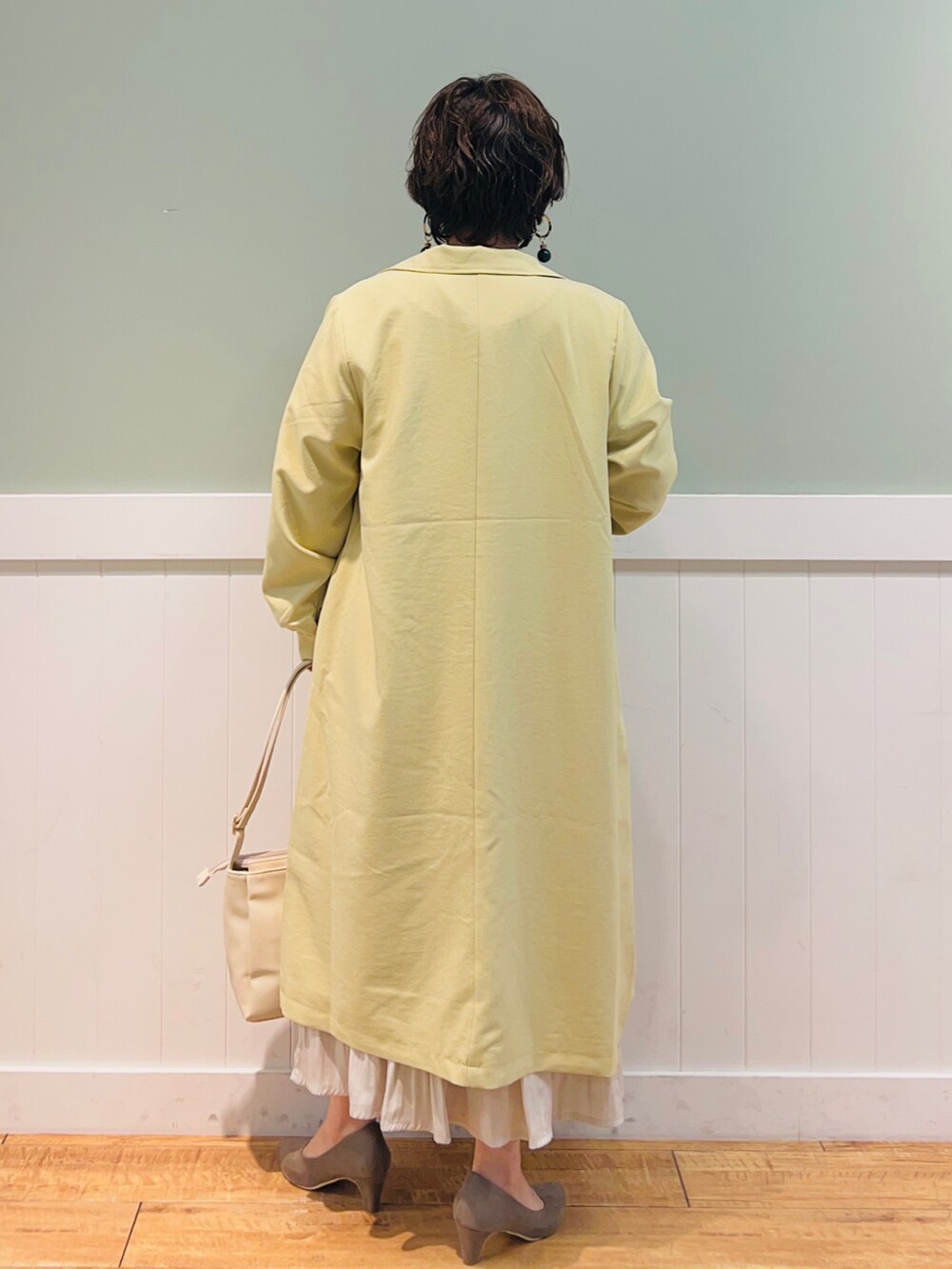 ベージュ系のその他トップス、イエロー系のステンカラーコート、ベージュ系のスカートを着用したレディースの春コーディネートの3枚目の写真