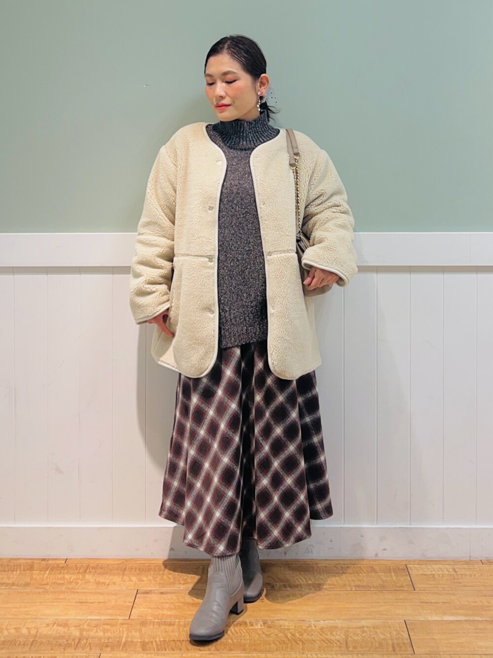 ブラウン系のニット/セーター、ホワイト系のブルゾン、ブラウン系のスカートを着用したレディースの冬コーディネートの2枚目の写真