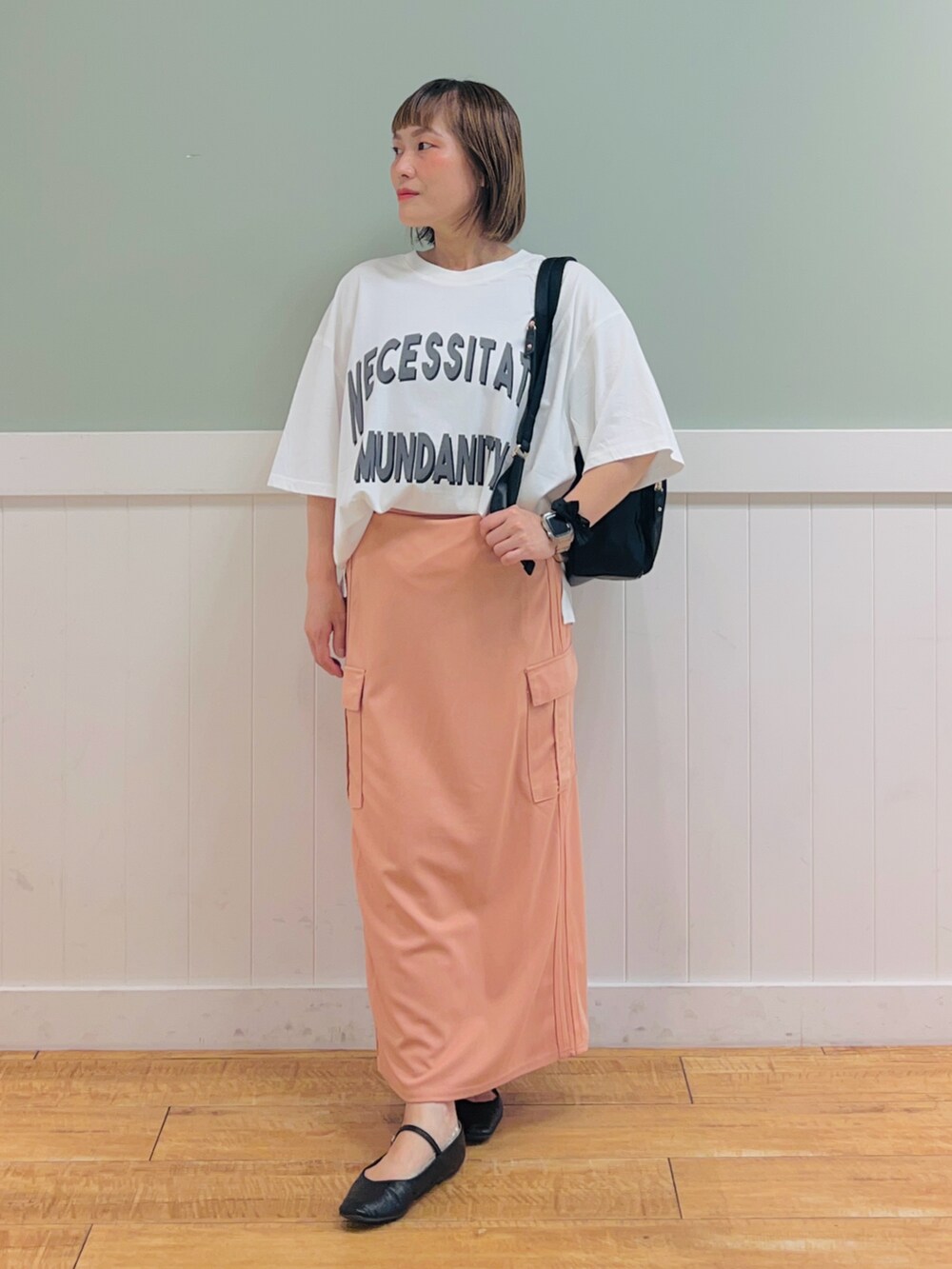 ブラック系のバックパック/リュック、ホワイト系のTシャツ/カットソー、オレンジ系のスカートを着用したレディースの夏コーディネートの4枚目の写真