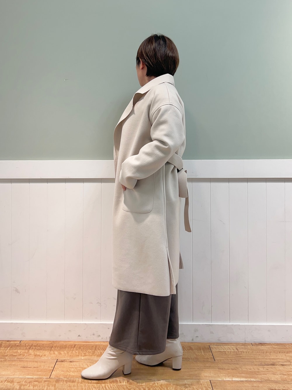 パープル系のニット/セーター、ベージュ系のチェスターコート、ベージュ系のショルダーバッグを着用したレディースの冬コーディネートの2枚目の写真