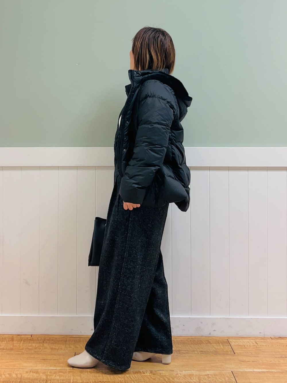 ブラック系のダウンジャケット/コート、ホワイト系のニット/セーター、ブラック系のトートバッグを着用したレディースの秋コーディネートの3枚目の写真