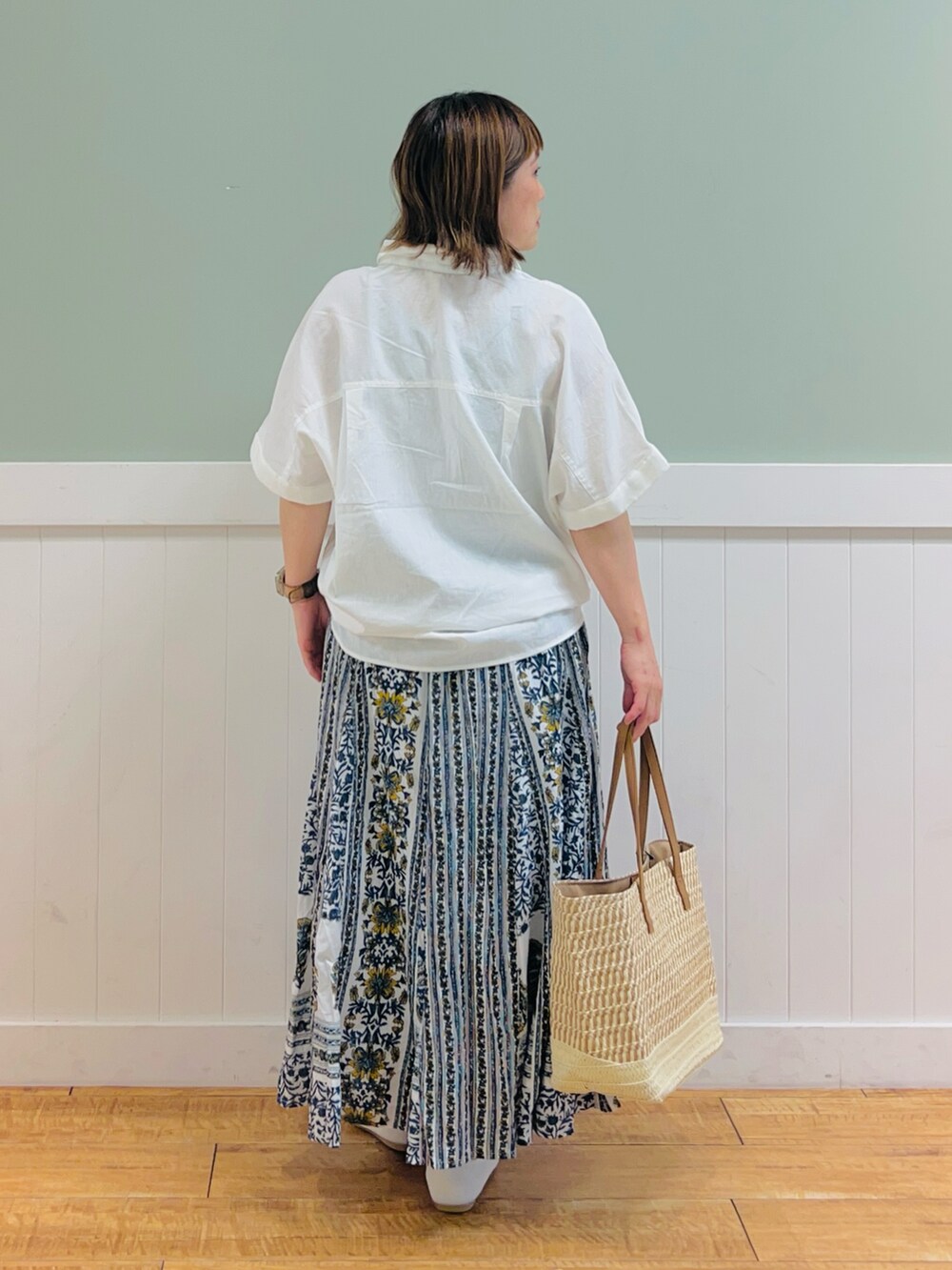 ホワイト系のシャツ/ブラウス、ブルー系のスカート、ベージュ系のトートバッグを着用したレディースの夏コーディネートの2枚目の写真