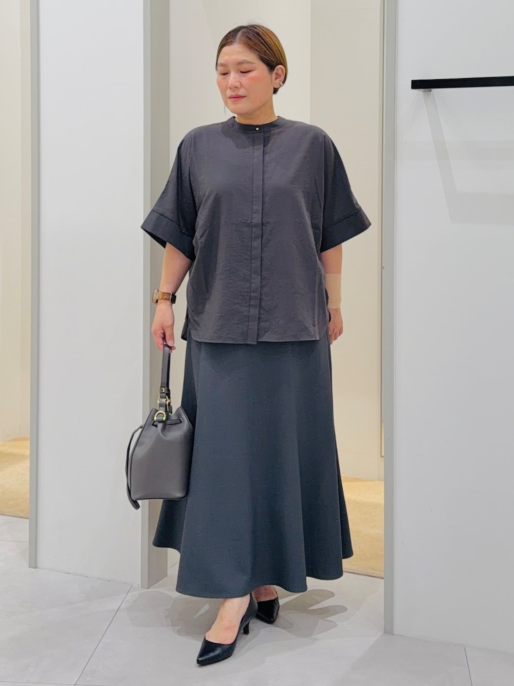 ブラック系のシャツ/ブラウス、グレー系のスカート、グレー系のショルダーバッグを着用したレディースの夏コーディネートの3枚目の写真