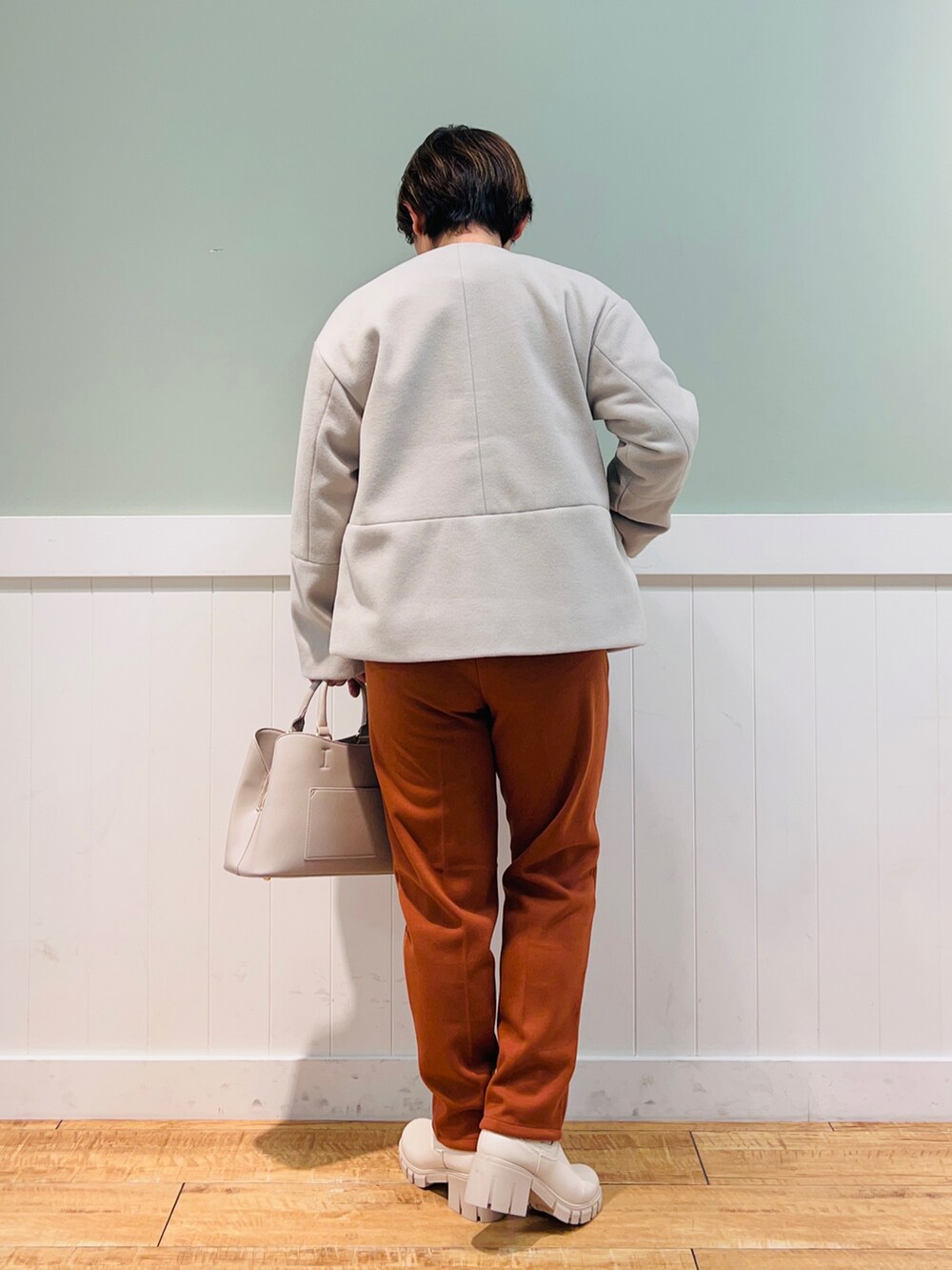 ベージュ系のノーカラーコート、ホワイト系のニット/セーター、グレー系のトートバッグを着用したレディースの冬コーディネートの2枚目の写真