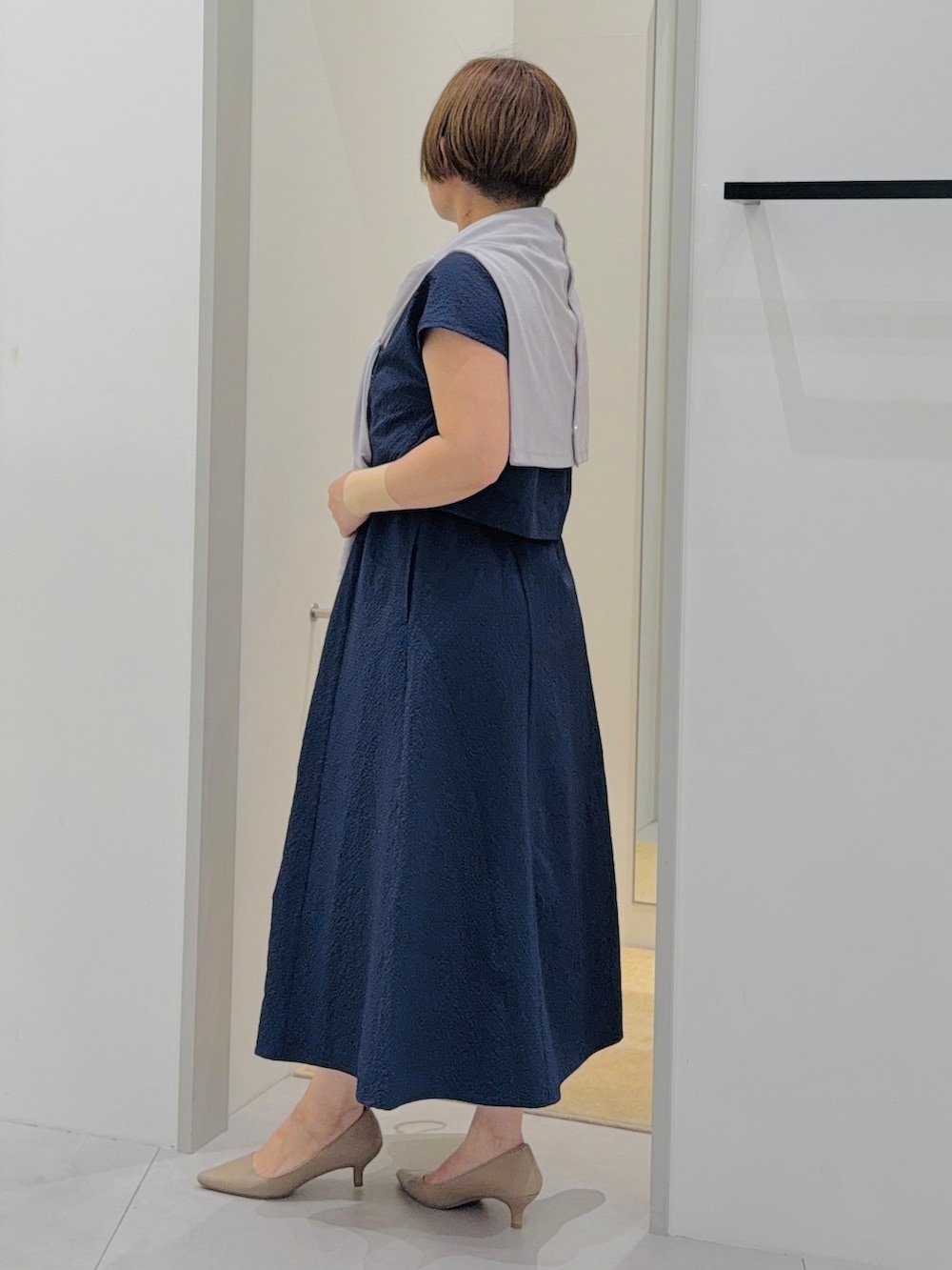 ブルー系のワンピース、グレー系のカーディガン/ボレロ、ホワイト系のショルダーバッグを着用したレディースの春コーディネートの3枚目の写真