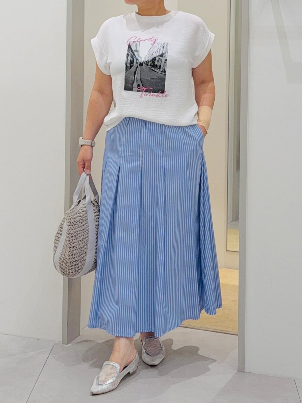 ホワイト系のTシャツ/カットソー、ブルー系のスカート、グレー系のトートバッグを着用したレディースの夏コーディネートの6枚目の写真
