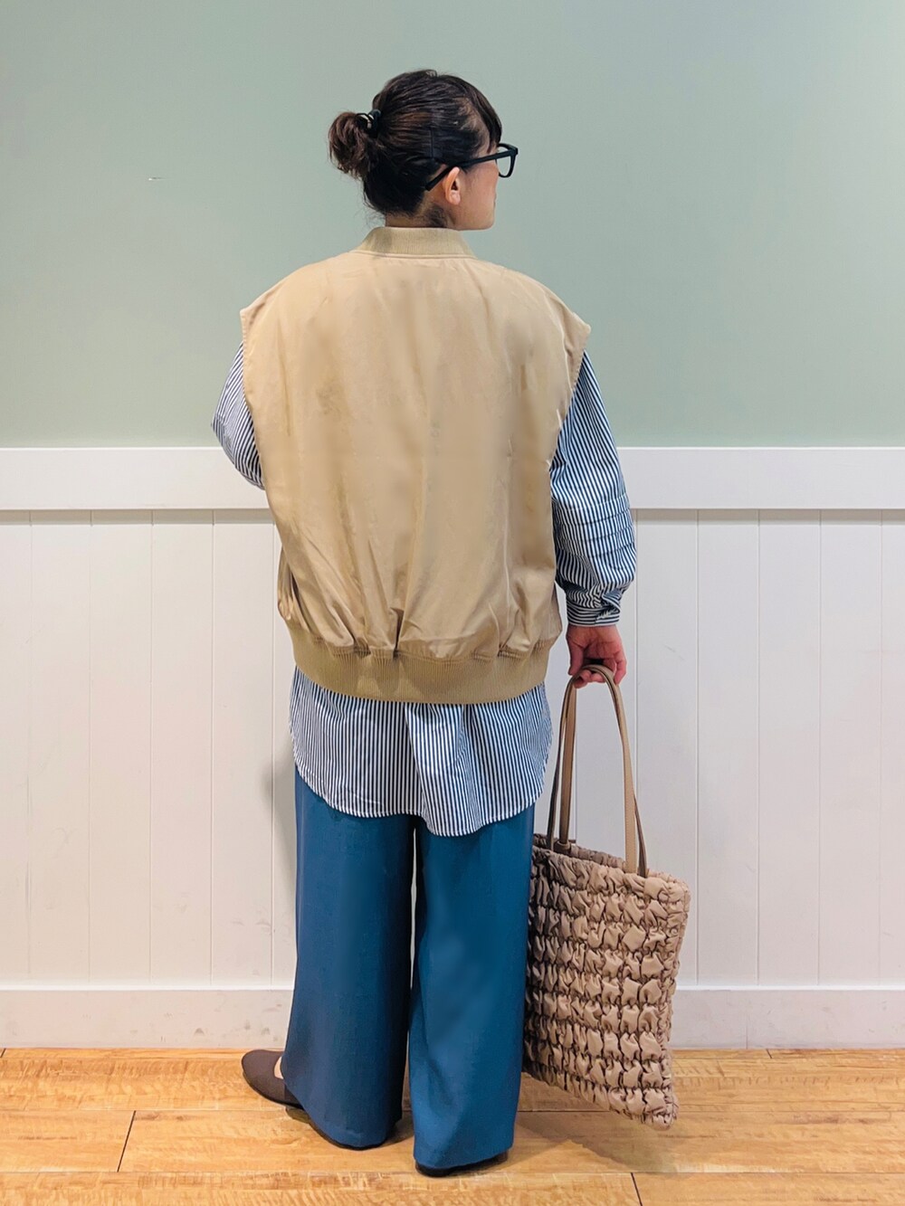 ブルー系のシャツ/ブラウス、ブラウン系のベスト、ベージュ系のバッグを着用したレディースの秋コーディネートの2枚目の写真