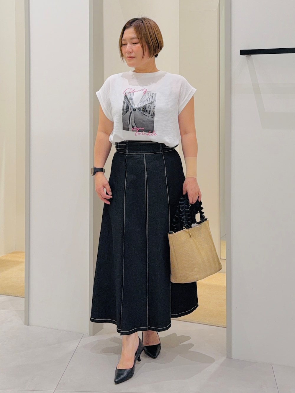 ホワイト系のTシャツ/カットソー、ブラック系のデニムスカート、ブラック系のパンプスを着用したレディースの夏コーディネートの2枚目の写真