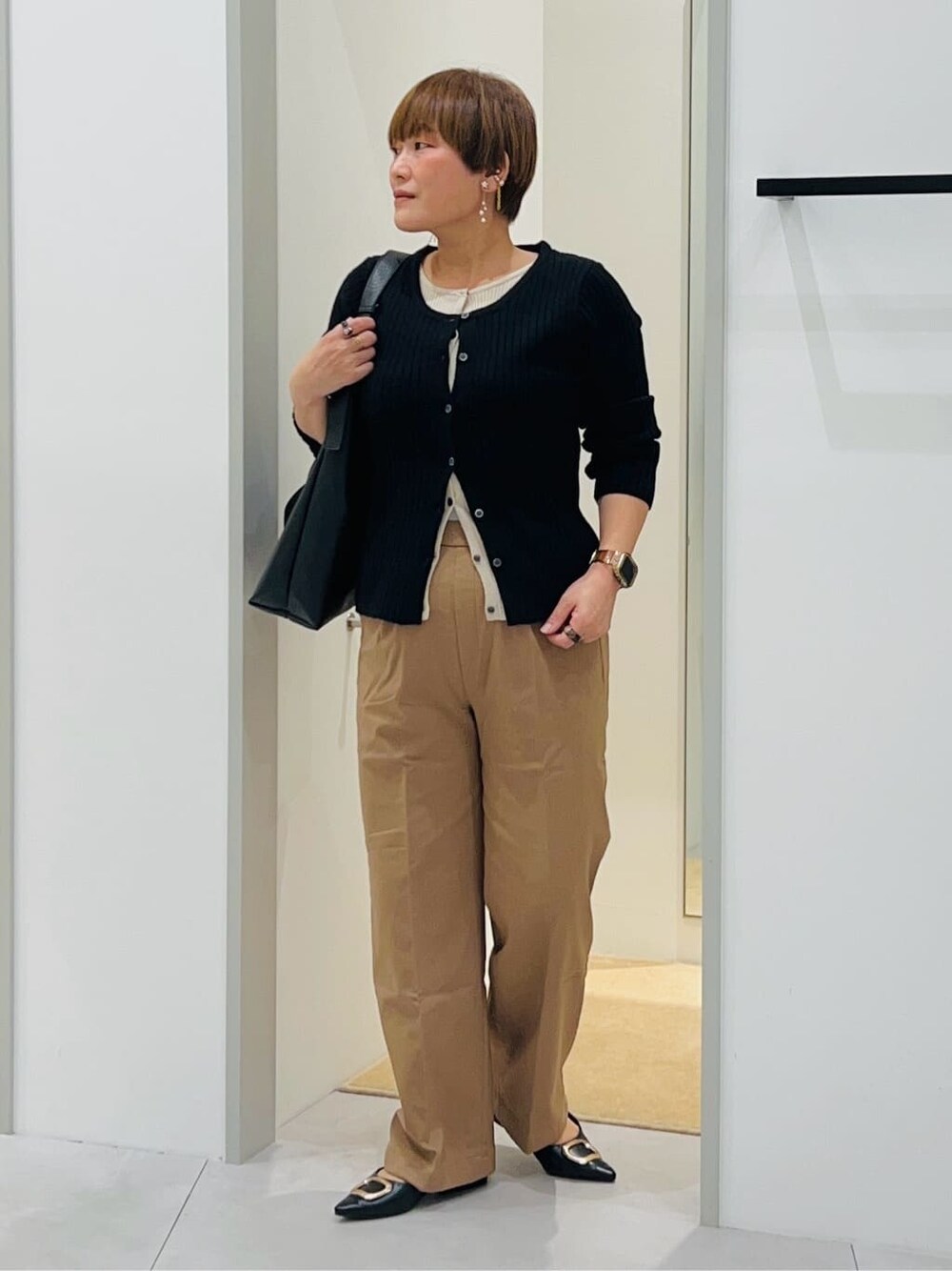ブラック系のニット/セーター、ベージュ系のその他パンツ、ブラック系のトートバッグを着用したレディースの秋コーディネートの2枚目の写真